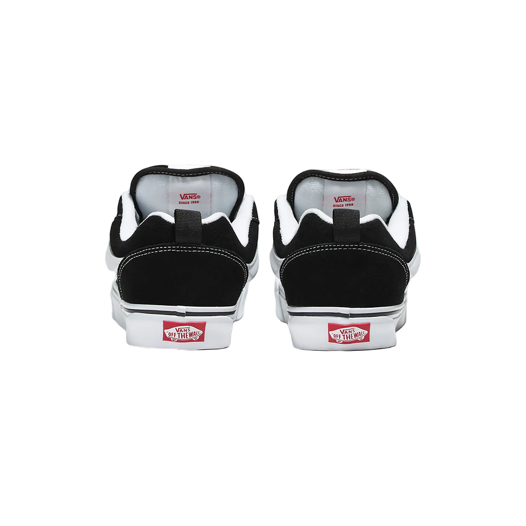 Black Vans sneakers with red and white labels on a light gray background