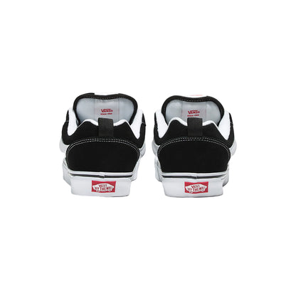 Black Vans sneakers with red and white labels on a light gray background