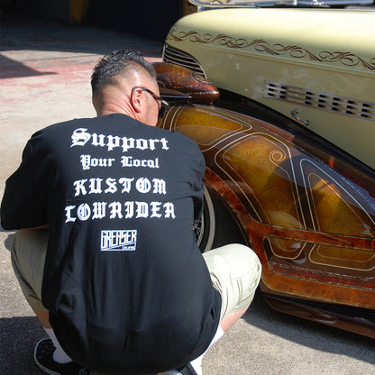 Man wearing a black t-shirt with text, inspecting a custom car.