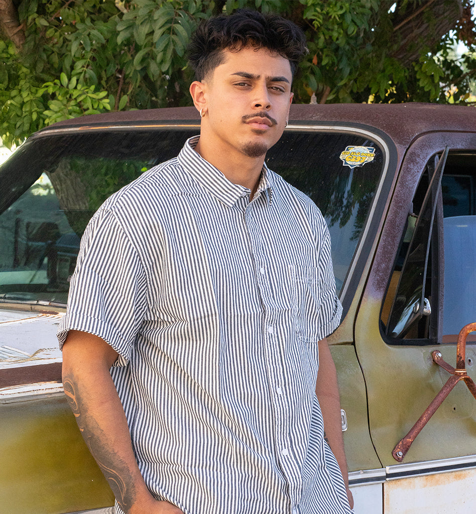 Man standing next to a vintage car with trees in the background