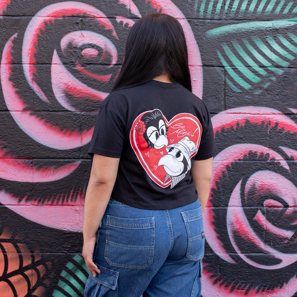 Person wearing a black t-shirt with a graphic design in front of a colorful mural.