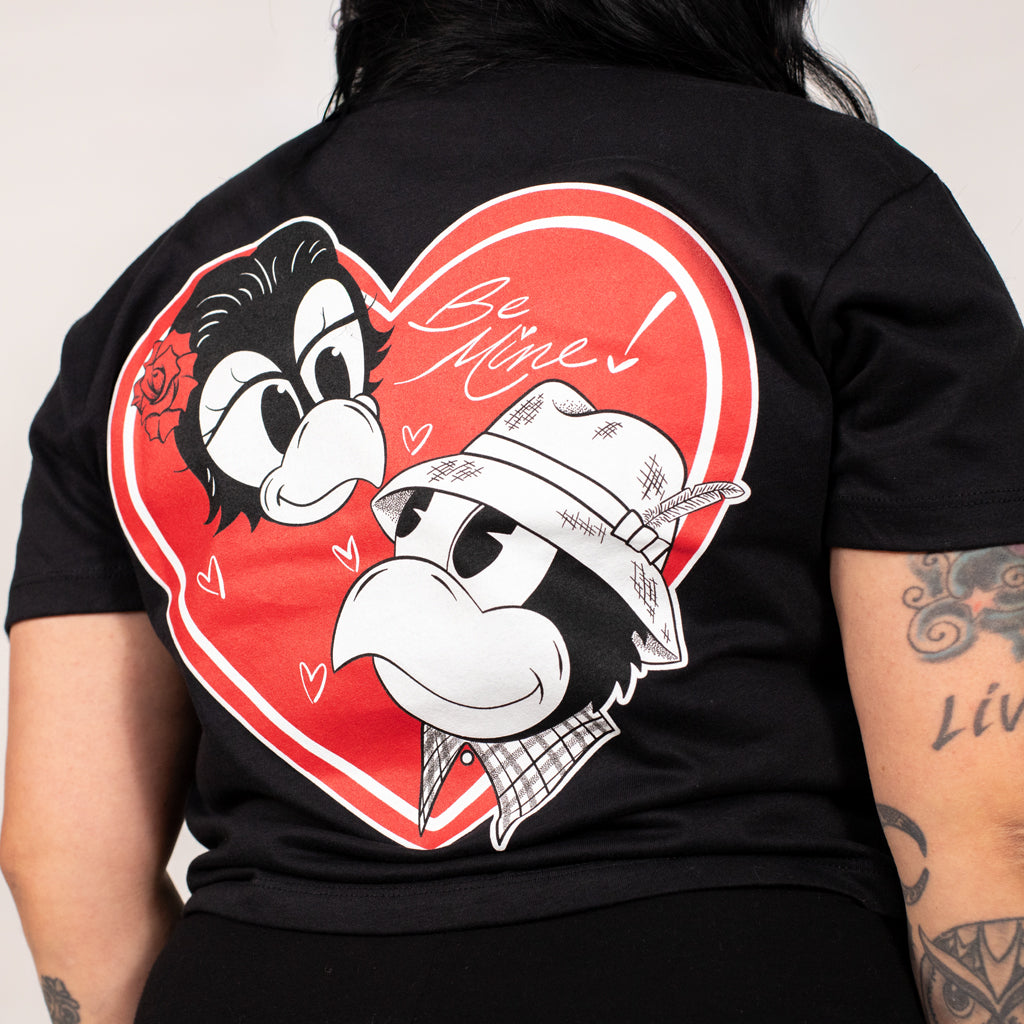 Black t-shirt with cartoon characters and 'Be Mine!' text on a red heart design.