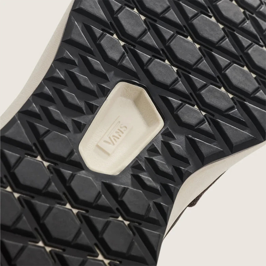 Close-up of a black textured sole with a white 'Vans' logo on a light background