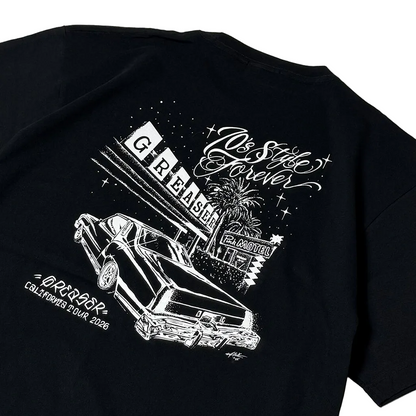 A close-up of a black short-sleeve T-shirt showing a large white graphic print on the back. The design features a retro car, a marquee reading 'G REASER', palm trees, stars, and stylized text including 'Do The Style Forever' and 'ORLANDO CALIFORNIA TOUR 2026'.