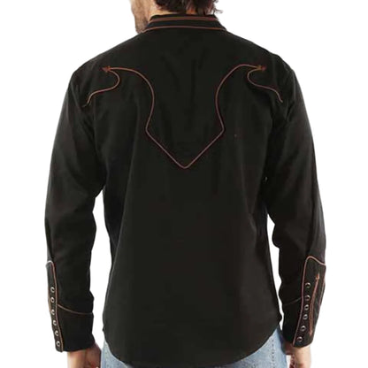 Man wearing a black embroidered shirt with blue jeans on a white background