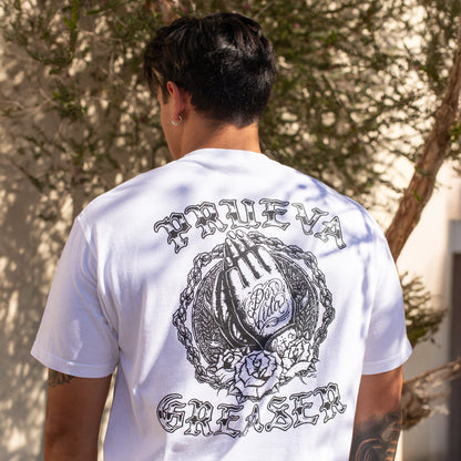 Person wearing a white t-shirt with black graphics and text outdoors