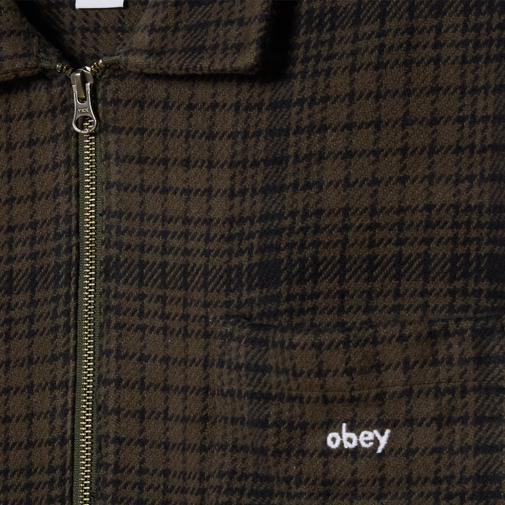 Brown plaid jacket with a zipper and 'obey' logo on a dark background