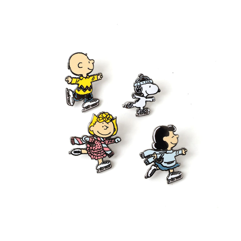 Four enamel pins of the peanuts characters on ice skates against a white background