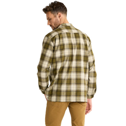 Man wearing a plaid shirt and brown pants on a white background