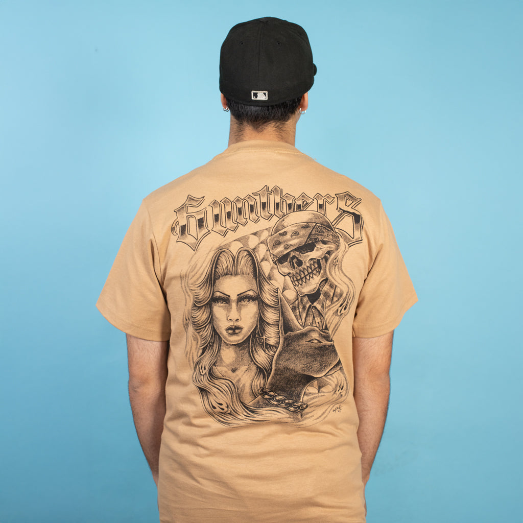 Person wearing a tan t-shirt with a graphic design on the back against a blue background