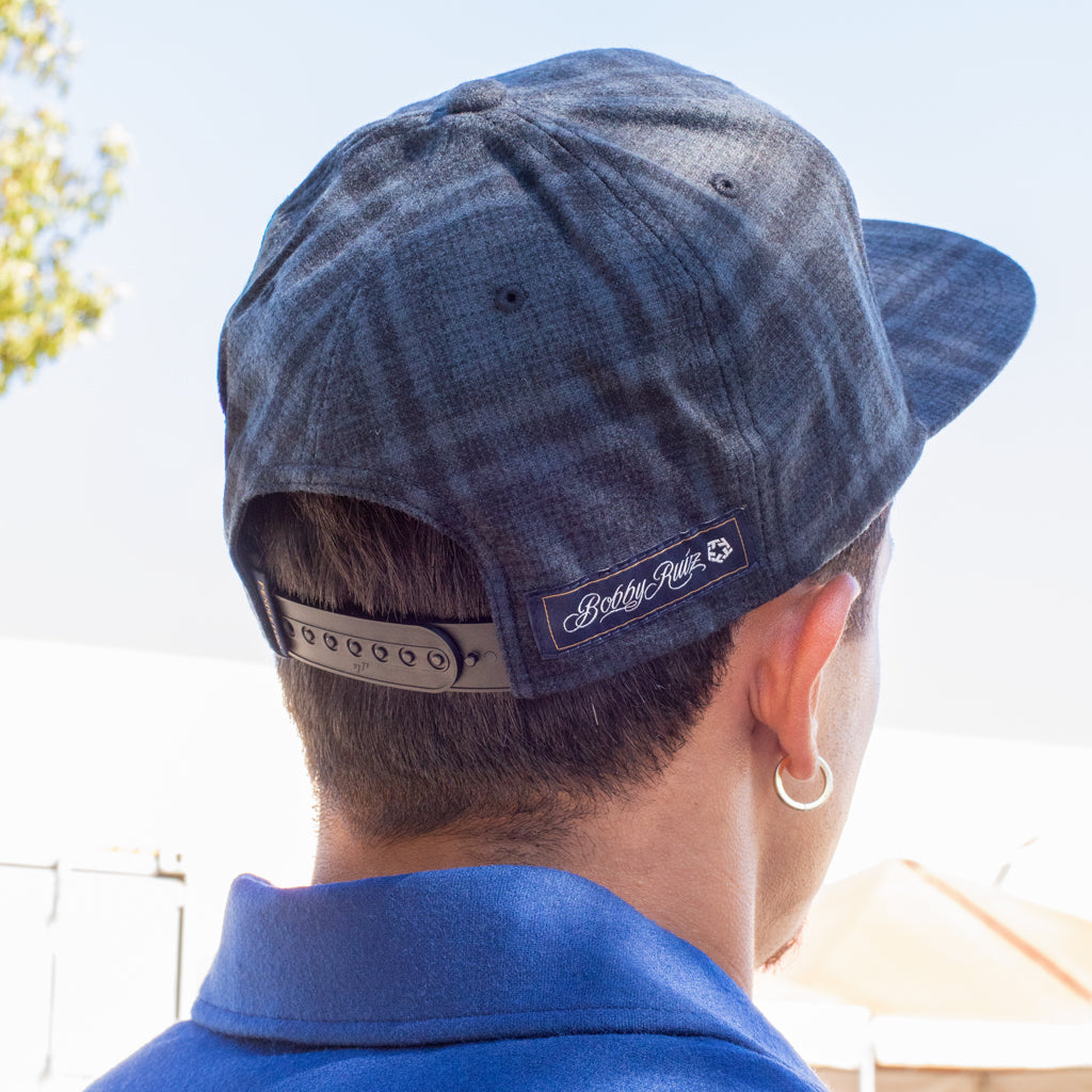 Person wearing a blue denim cap with a brand logo, looking away from the camera.