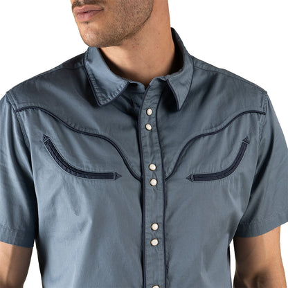 Man wearing a blue short-sleeve shirt with decorative stitching on a white background
