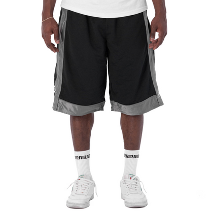 A person wearing black athletic shorts with gray side panels and hem trim, paired with a white t-shirt, white socks, and white sneakers, shown from the waist down on a white studio background.