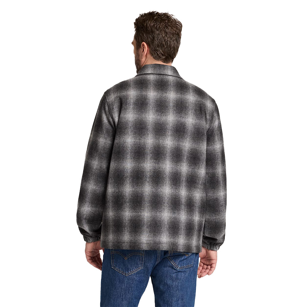 Man wearing a gray and black plaid shirt on a white background
