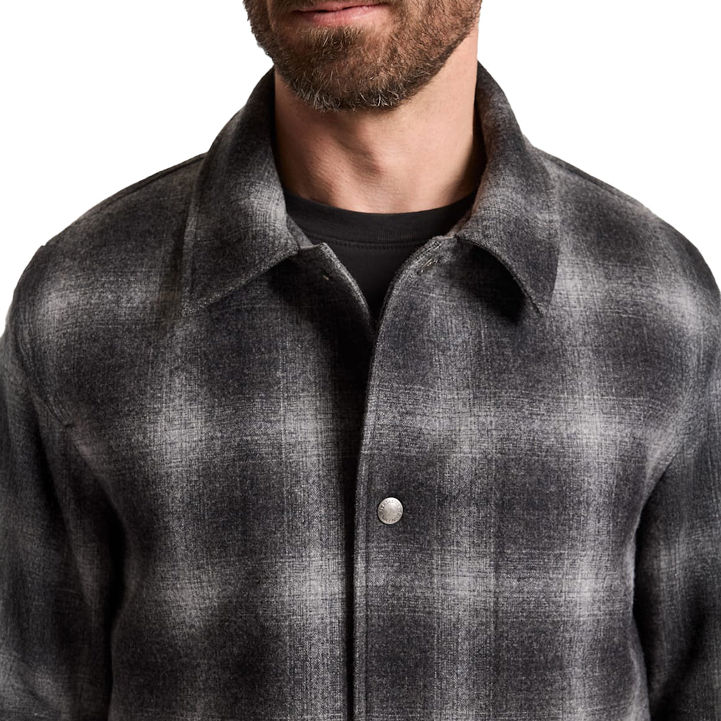 Man wearing a gray plaid shirt with a white background