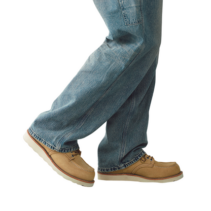 Person wearing blue jeans and tan shoes on a white background