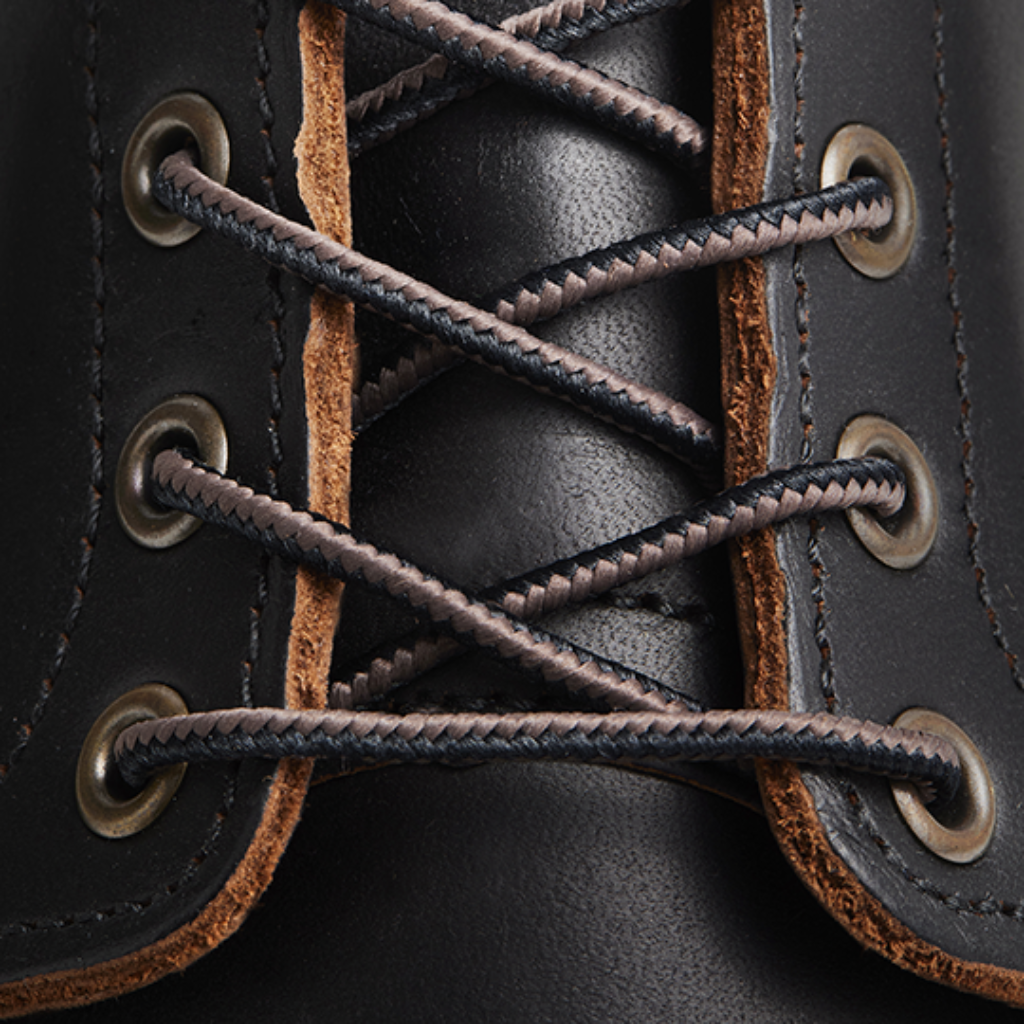 Close-up of black leather boot with brown laces and eyelets
