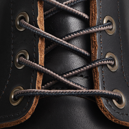 Close-up of black leather boot with brown laces and eyelets