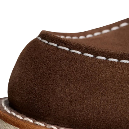 Close-up of a brown suede shoe with white stitching on a white background