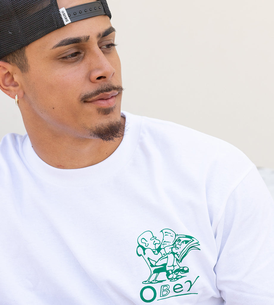 Man wearing a white t-shirt with a green graphic and 'Obey' logo.