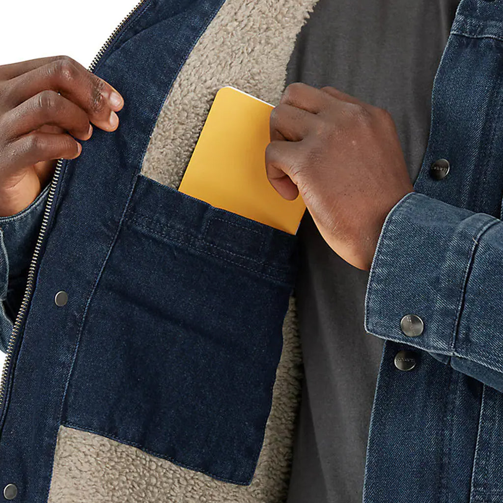 Person placing a yellow note pad into a blue denim jacket with a sherpa lining.
