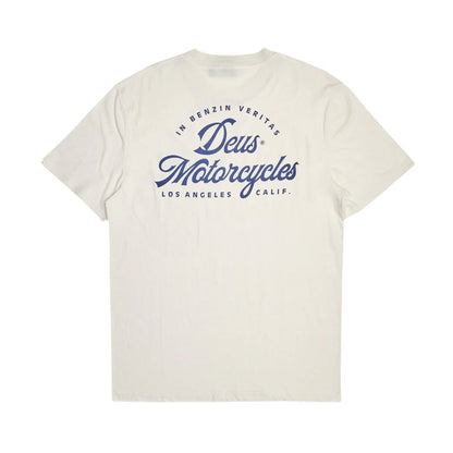 An off-white short-sleeve t-shirt with a blue graphic print on the front reading 'Deus Motorcycles' and 'In Benzin Veritas Los Angeles, Calif.' on a solid white background.
