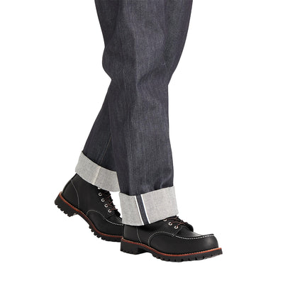 Black boots with white laces worn with gray pants on a white background