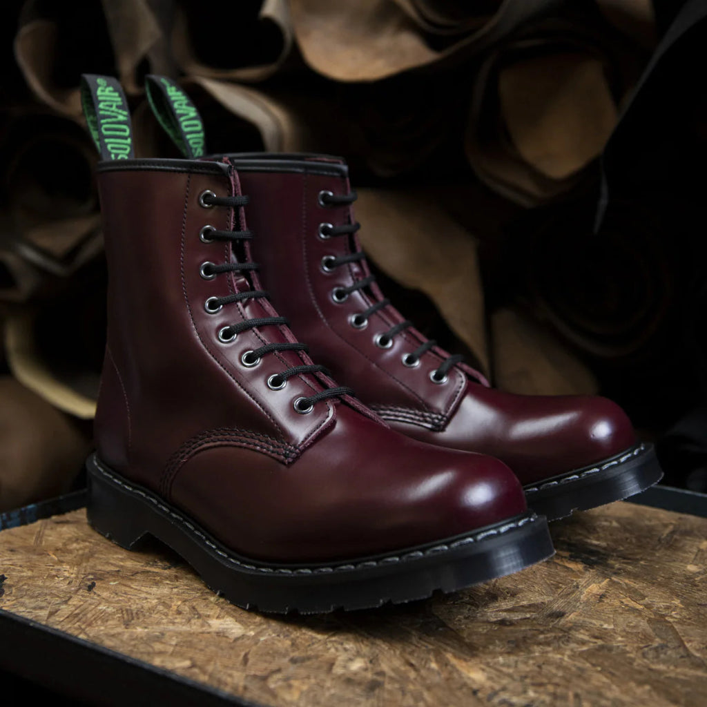 Pair of maroon boots with a brand tag on a wooden surface