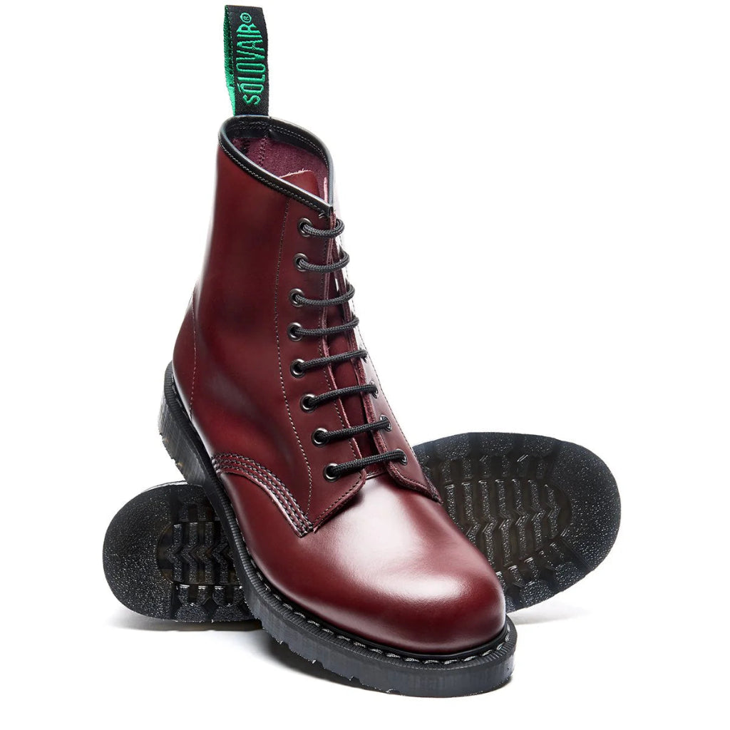 Maroon leather boots with black soles on a white background