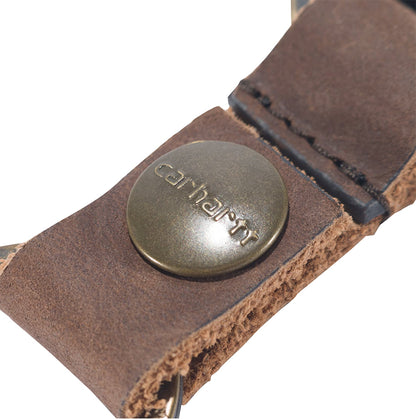 Close-up of a brown leather strap with a metal button featuring the Carhartt logo on a white background.