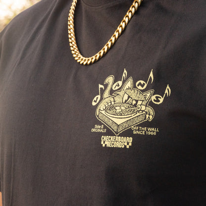Black t-shirt with a gold graphic design and text, worn by a person.