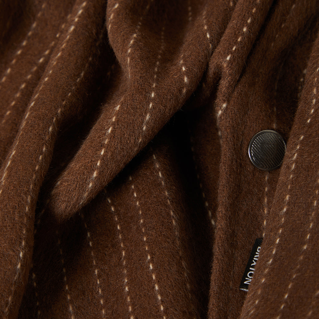 Close-up of a brown textured fabric with a button and visible brand name.
