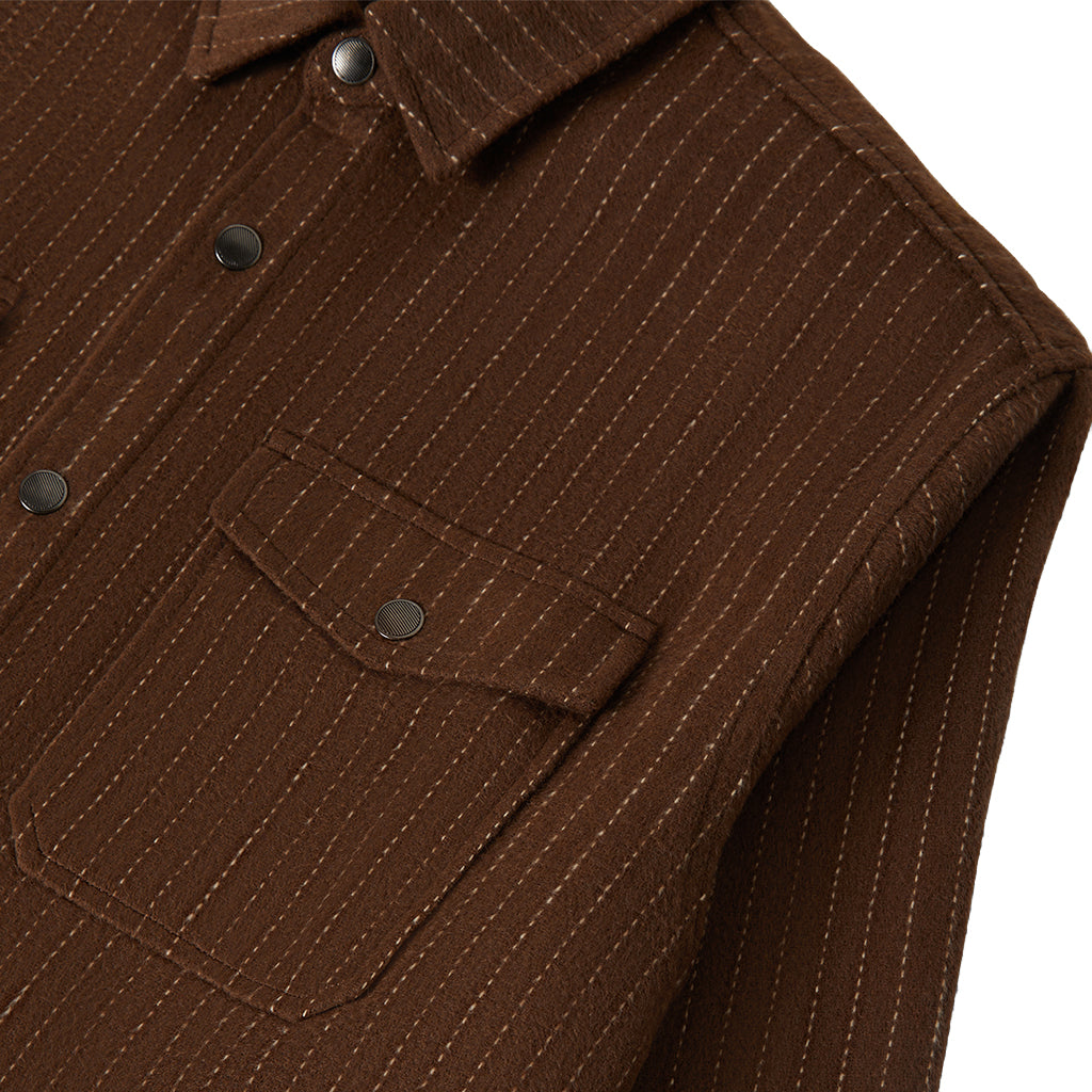 Close-up of a brown jacket with a pocket and button details on a white background