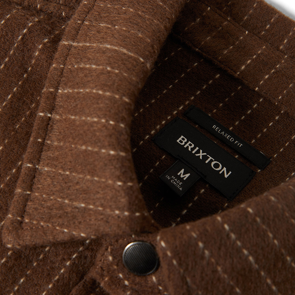 Close-up of a brown jacket with a Brixton label on a textured fabric background