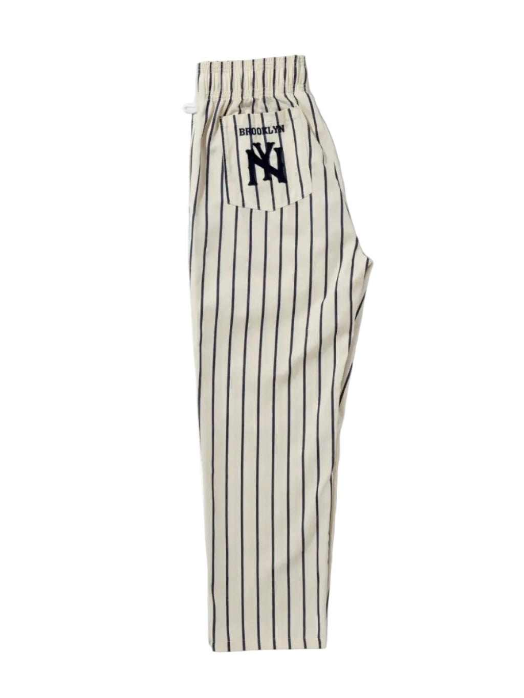A pair of cream-colored pinstriped pants with black vertical stripes, featuring a drawstring waistband and a back pocket with a black embroidered 'Brooklyn' 'NY' logo. 