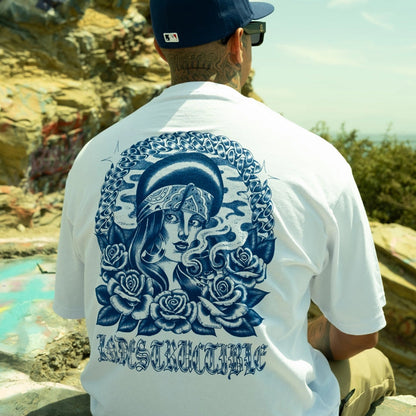 Person wearing a white t-shirt with a blue graphic design outdoors.