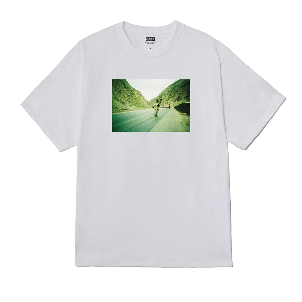 White t-shirt with a graphic of a person riding a bike on a road surrounded by greenery, brand 'G/FORE' visible.