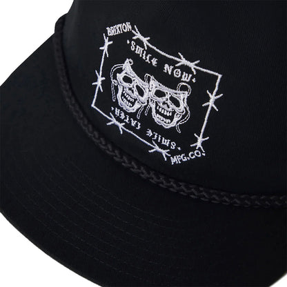Black cap with white embroidered design featuring skulls and text on a white background