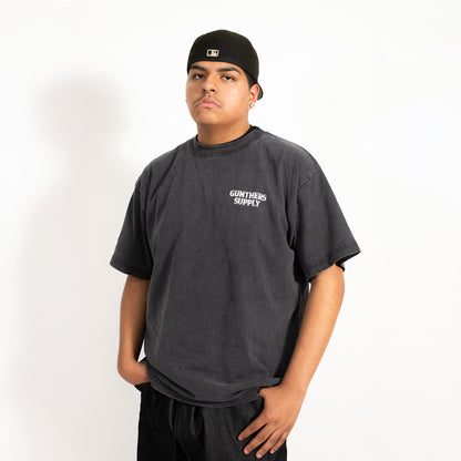 Person wearing a dark gray t-shirt with 'Gunters Supply' logo on a white background