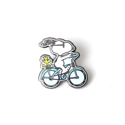 Enamel pin of Snoopy and Woodstock riding a bicycle on a white background