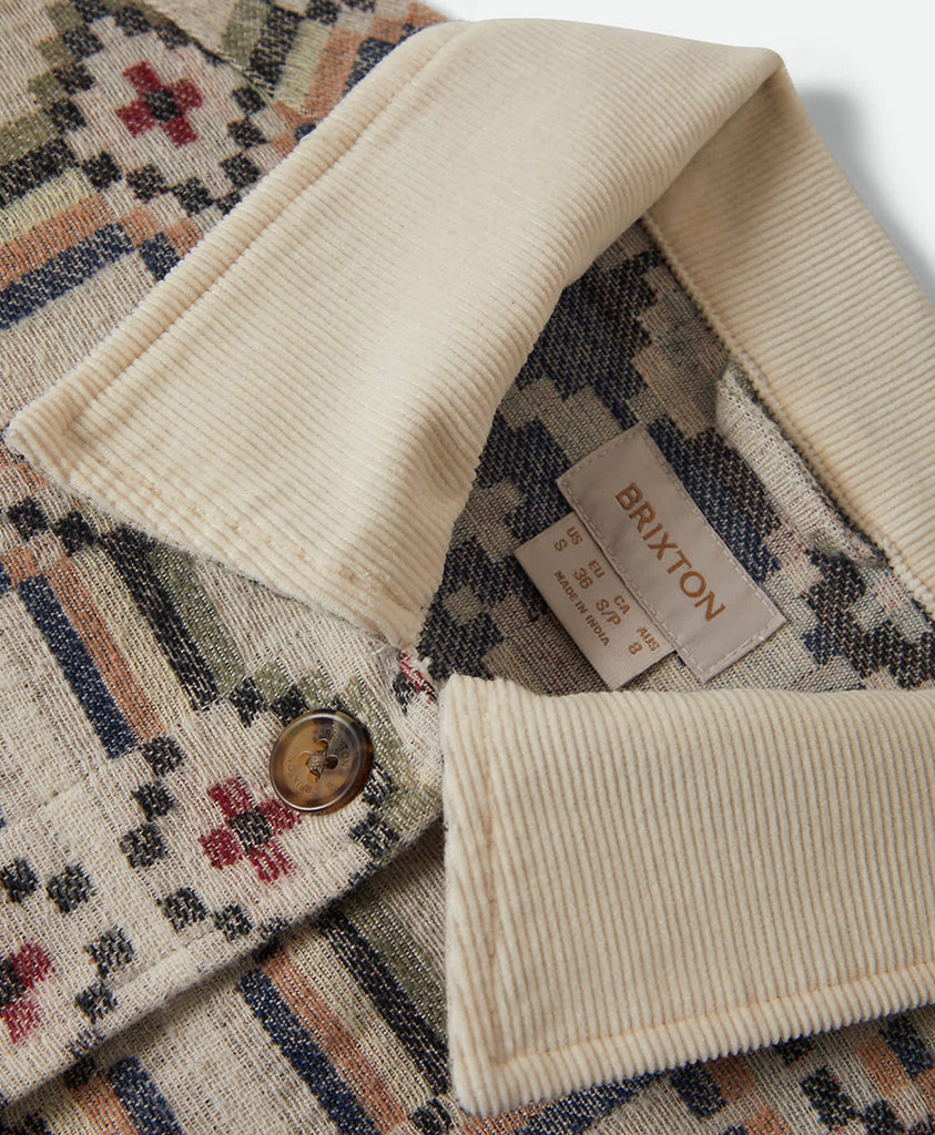 Close-up of a jacket collar with a Brixton label on a patterned fabric background