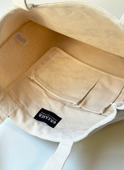 Beige tote bag with a visible Greaser label on a light background