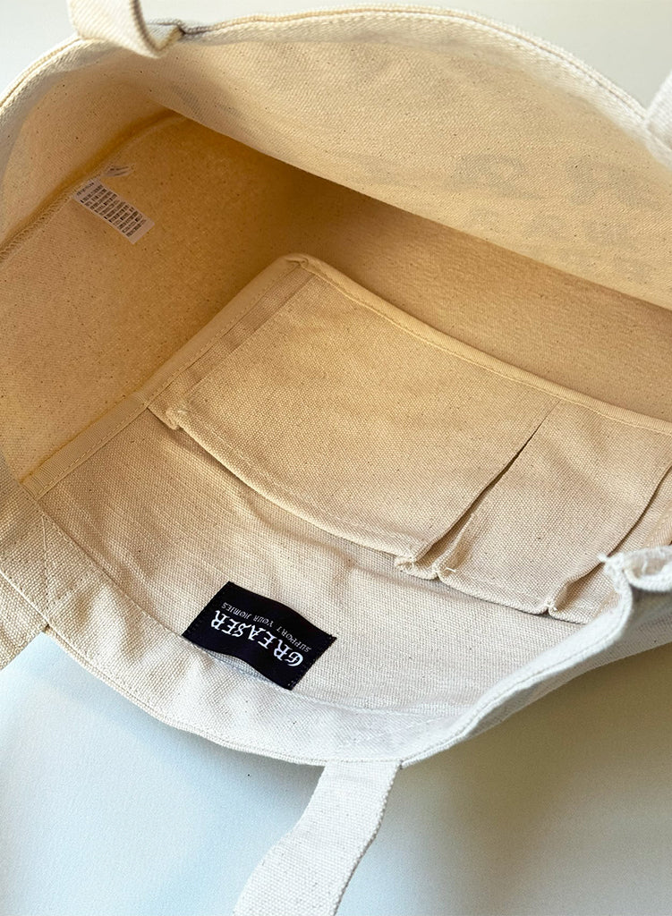 Beige tote bag with a visible Greaser label on a light background