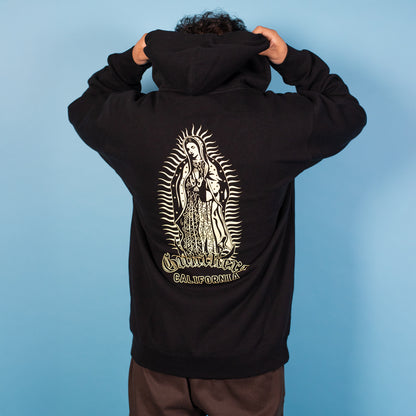 Person wearing a black hoodie with a religious icon design on the back against a blue background