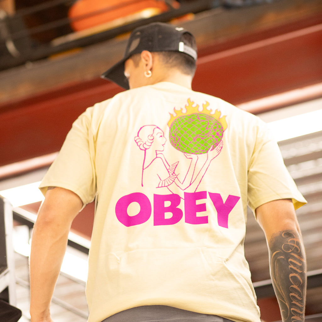 Person wearing a yellow 'Obey' t-shirt with a graphic design on the back.