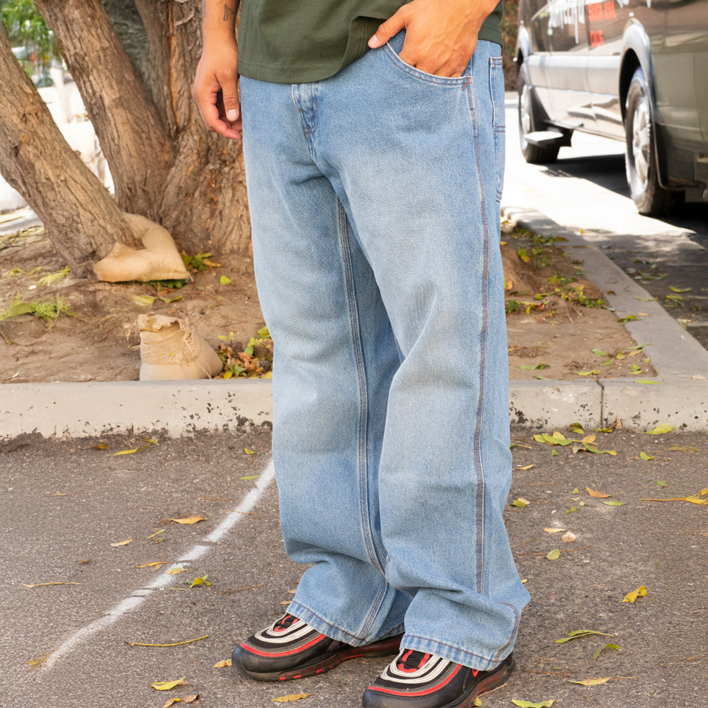 Person wearing blue jeans and colorful shoes on a street.