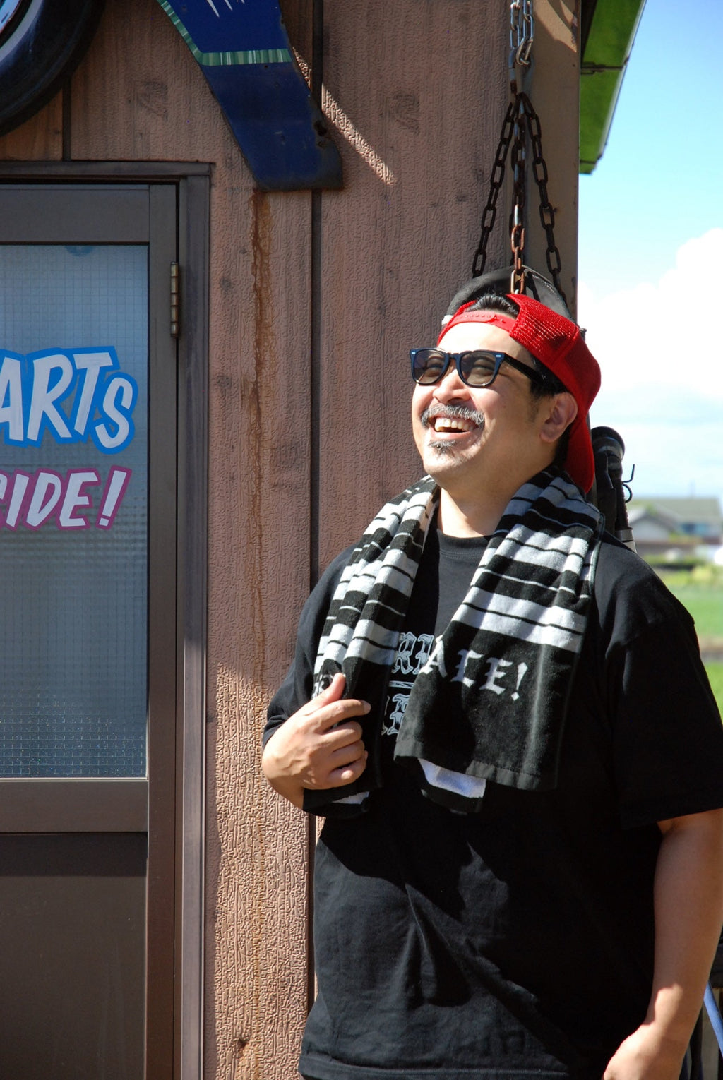 Man wearing a hat and sunglasses standing in front of a store 