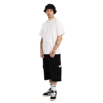 A model wearing a white crewneck t-shirt, black cargo shorts, white socks, and black and white sneakers, standing against a solid white background.