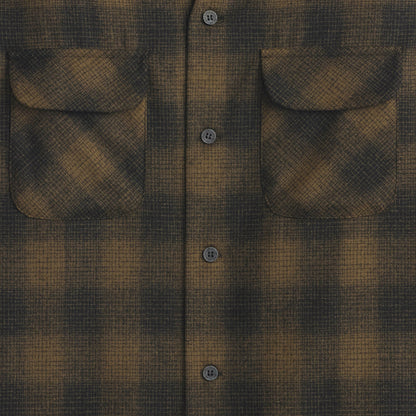 Close-up of a brown and black plaid shirt with button details.
