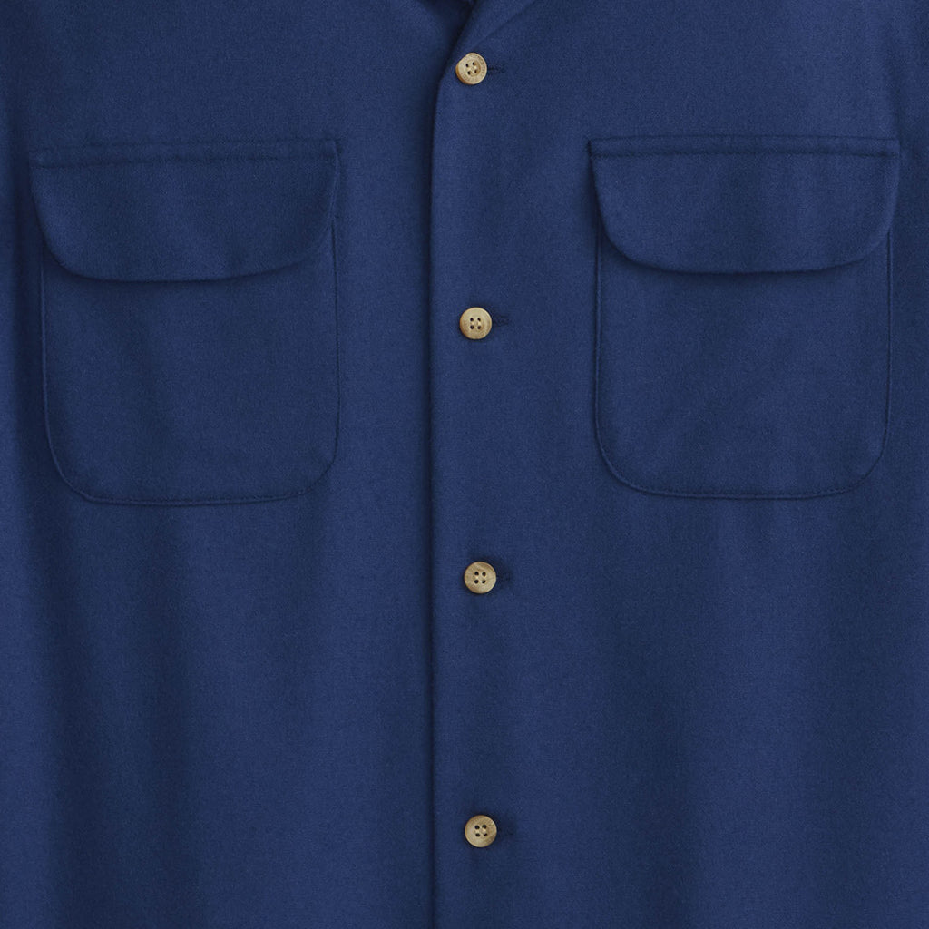 Close-up of a blue shirt with button details on a plain background